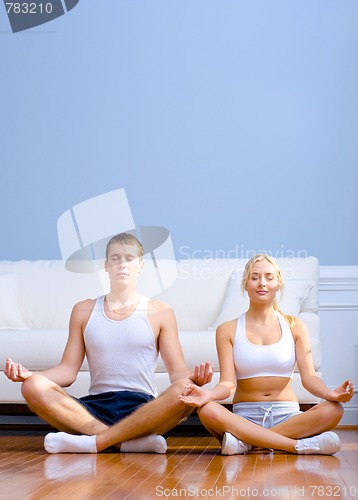 Image of Young Couple Sitting on Floor Meditating