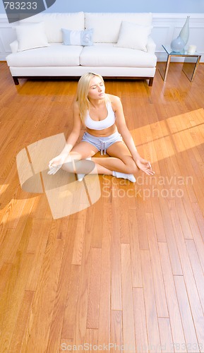 Image of Young Woman Sitting on Wood Floor Meditating