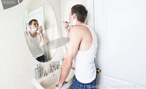 Image of Young Man in Bathroom Shaving