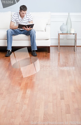 Image of Young Man Sitting on Sofa Reading