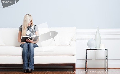 Image of Woman Sitting on Couch and Reading Book