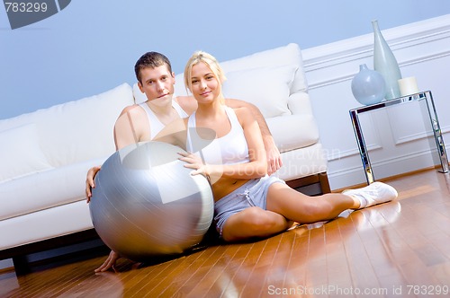 Image of Couple Sitting on Floor With Silver Exercise Ball