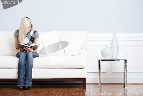 Image of Young Woman Sitting on Sofa Reading