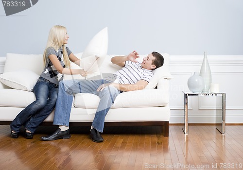 Image of Young Woman Smiling and Hitting Young Man With Pillow