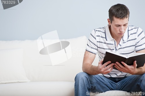 Image of Young Man Sitting on Sofa Reading