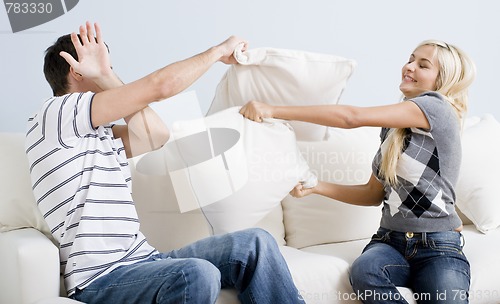 Image of Young Couple Having a Pillow Fight on Sofa