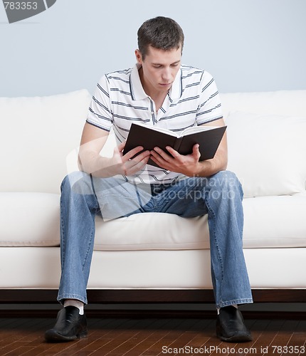 Image of Young Man Sitting on Sofa Reading