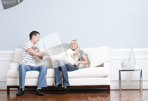 Image of Young Couple Having a Pillow Fight on Sofa