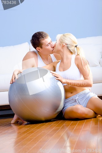 Image of Couple Sitting on Floor With Silver Exercise Ball Kissing