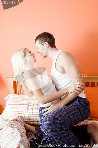 Image of Young Couple Kneeling on Bed Embracing