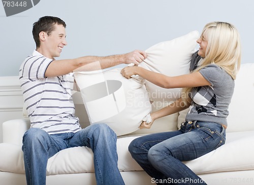 Image of Young Couple Having a Pillow Fight on Sofa