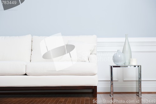 Image of White Sofa and Glass End Table Against Blue Wall