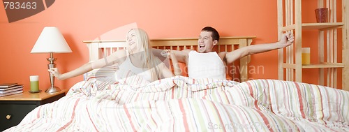 Image of Young Couple Lying in Bed Stretching