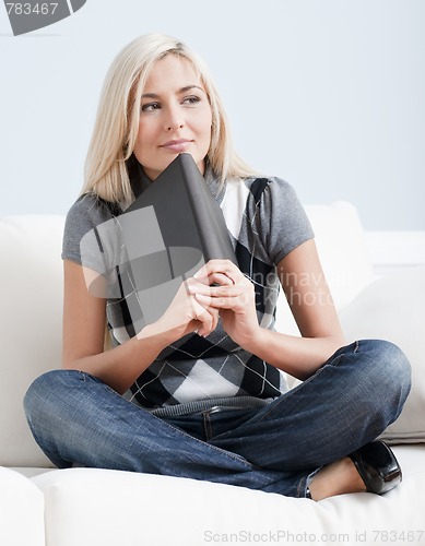 Image of Contemplative Woman Sitting on Couch and Holding a Book