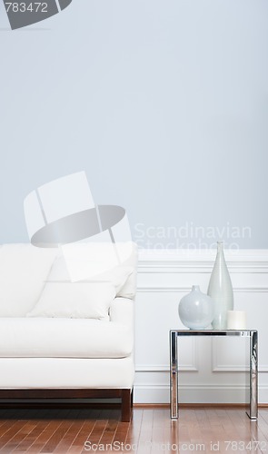 Image of White Sofa and Glass End Table Against Blue Wall