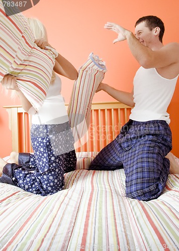 Image of Young Couple Kneeling on Bed Having a Pillow Fight