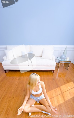 Image of Young Woman Sitting on Wood Floor Meditating