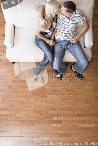 Image of Young Couple Sitting on Love Seat Kissing