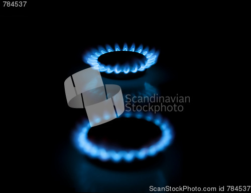 Image of Two gas burners with flames on dark background