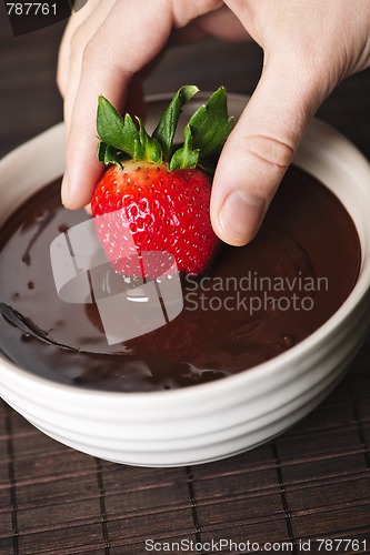 Image of Hand dipping strawberry in chocolate