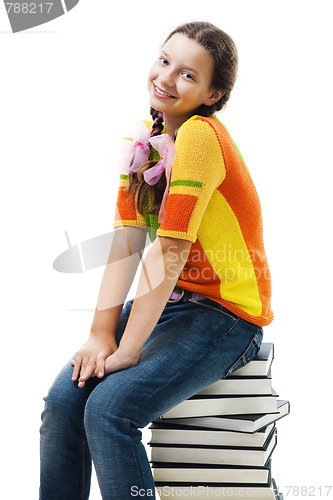 Image of Happy teenager sit on stack of books