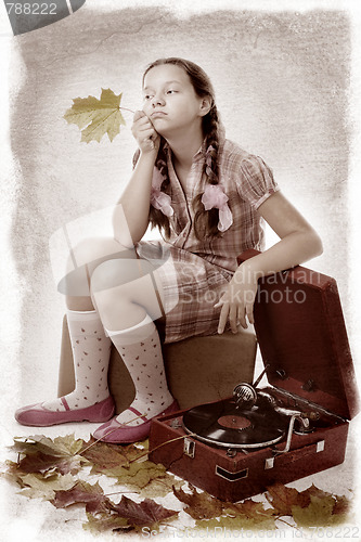 Image of  kid sitting holding maple leaf with gramophone