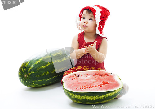 Image of Baby with red dress and cap sit with watermelon