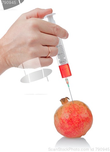 Image of hand holds the syringe on pomegranate