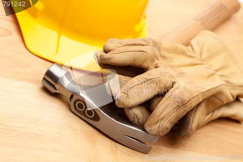 Image of Yellow Hard Hat, Gloves and Hammer on Wood