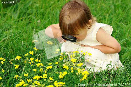 Image of Child looking at flowers through magnifying glass