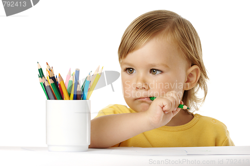 Image of Child bites green crayon and thinks about ideas