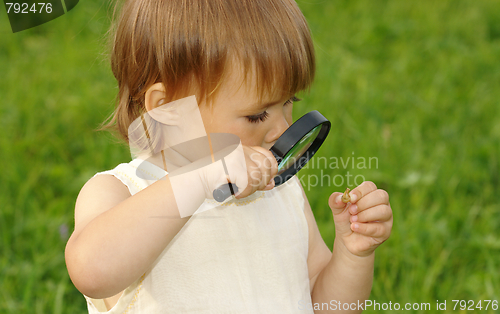 Image of Child looking at snail through magnifying glass