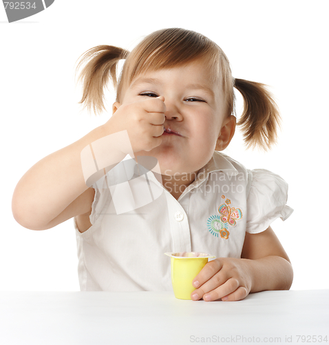 Image of Funny Little girl eats yogurt
