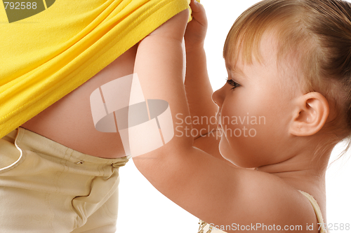 Image of Daughter looking at pregnant mother's belly