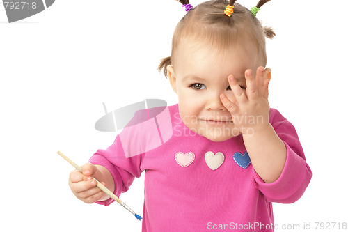 Image of Little girl with paintbrush clasping hand to cheek
