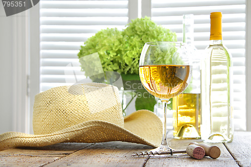 Image of Glass of wine with straw hat on table