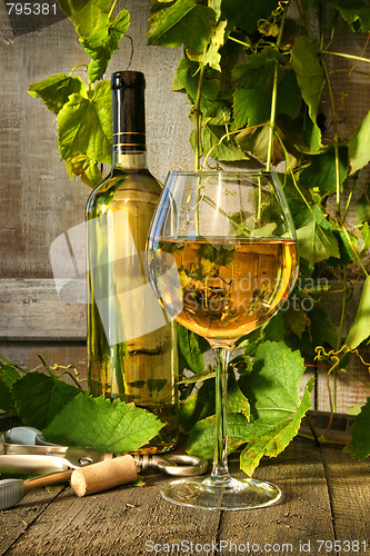 Image of Glass of white wine and bottle on barrel 