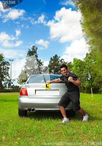 Image of Happy male driver holding learner licence plates beside car