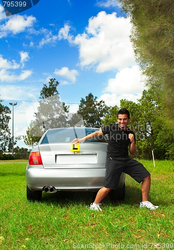 Image of Excited male holding licence permit plates beside silver car