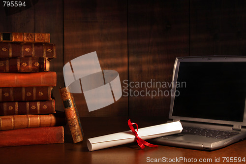 Image of Antique books, diploma with laptop on desk