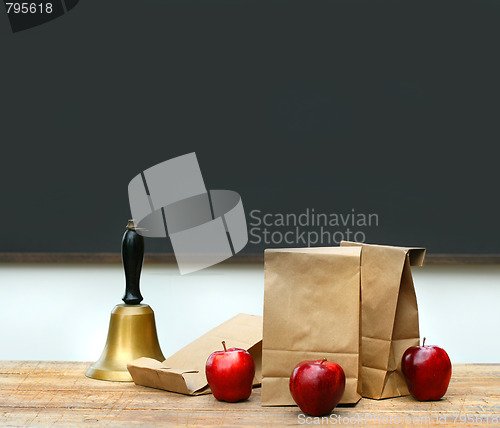 Image of Lunch bags with apples and school bell on desk