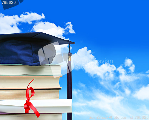 Image of Stack of books with diploma against blue sky