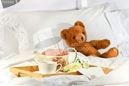 Image of Tea in bed with teddy on white sheets