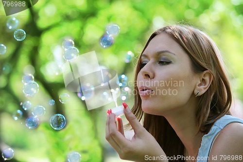 Image of young woman blows soap bubbles