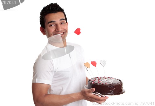 Image of Man holding delicious chocolate cake decorated with love hearts