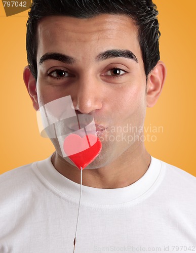 Image of Amorous man kissing love heart on a stick