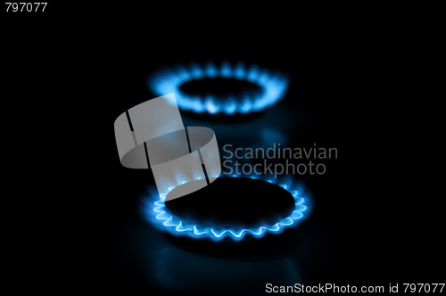 Image of Two gas burners with flames on dark background