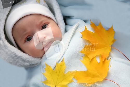 Image of infant and autumn yellow maple leaf