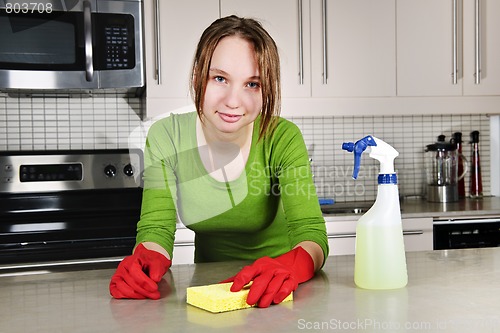 Image of Young woman cleaning kitchen