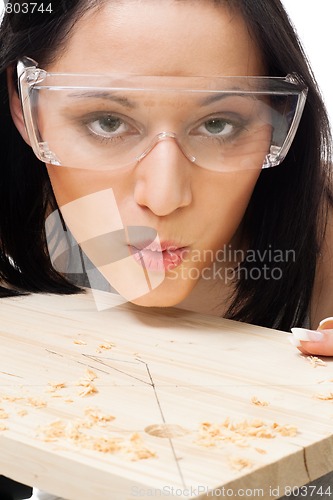 Image of Woman carpenter blow away scobs